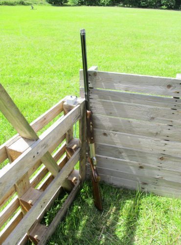 Following a clay shooting, a rifle is propped up against a wooden fence. Following a clay shooting, a rifle is propped up against a wooden fence.