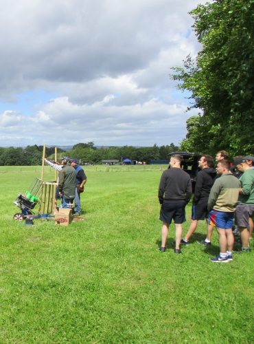 A group is watching a colleague shoot clay pigeons. A group is watching a colleague shoot clay pigeons.